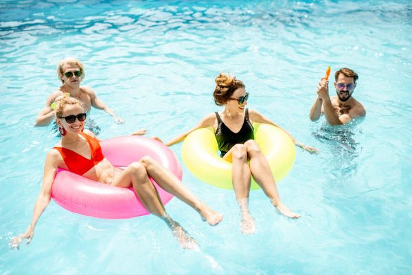 Group of a happy friends having fun, swimming with inflatable rings in the swimming pool outdoors during the summertime in winter haven, fl